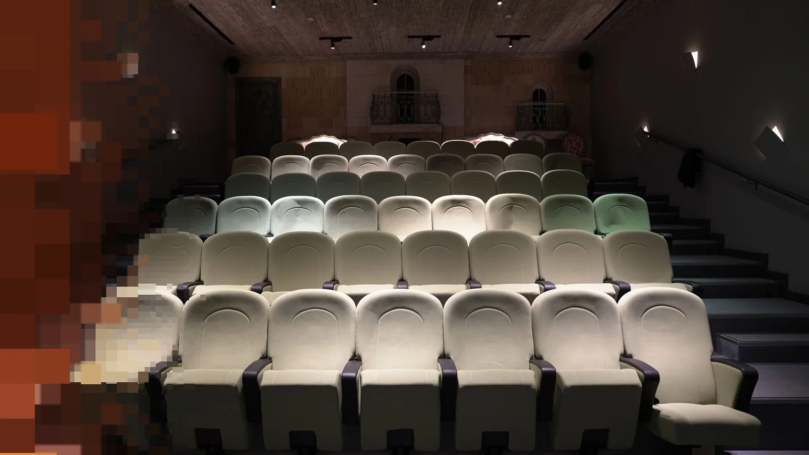 En tom liten teatersal med rader av lyse seter og varmt lys fra lampene i taket