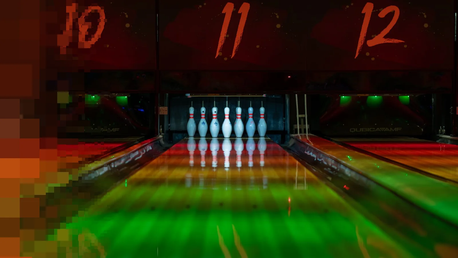 Bowlingbaner badet i grønt og rødt lys med kjegler oppstilt under nummerskiltene 10, 11 og 12