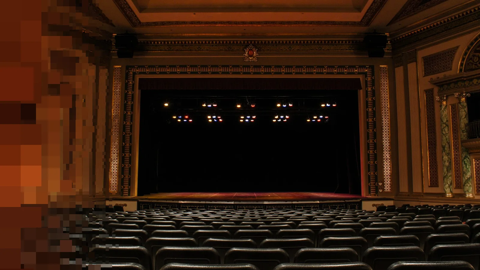 Gammel teatersal med utsmykkede balkonger og lysekroner sett fra parkett