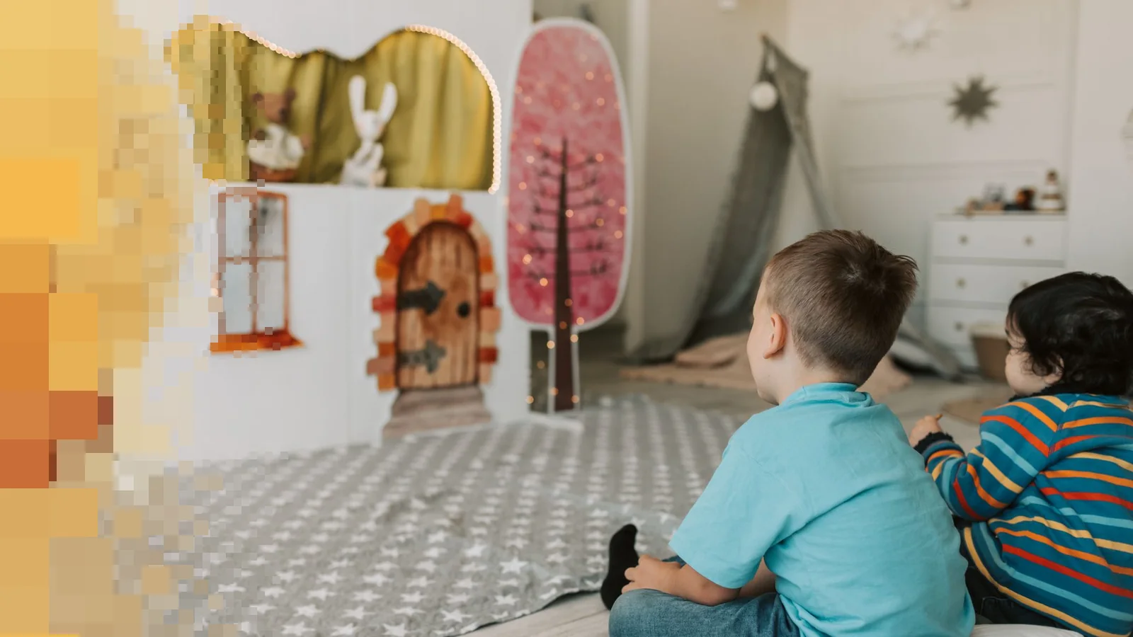 To barn sitter på gulvet og ser mot en liten scene med dyr og et tre