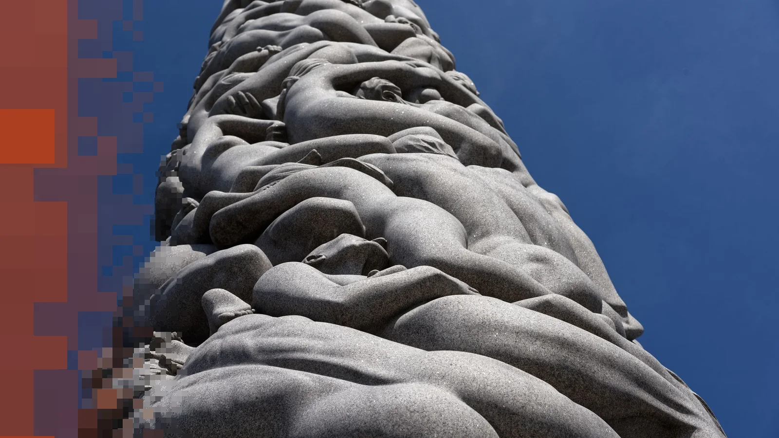 Granittfigurer som slynger seg oppover Monolitten i Vigelandsparken, sett nedenfra mot blå himmel