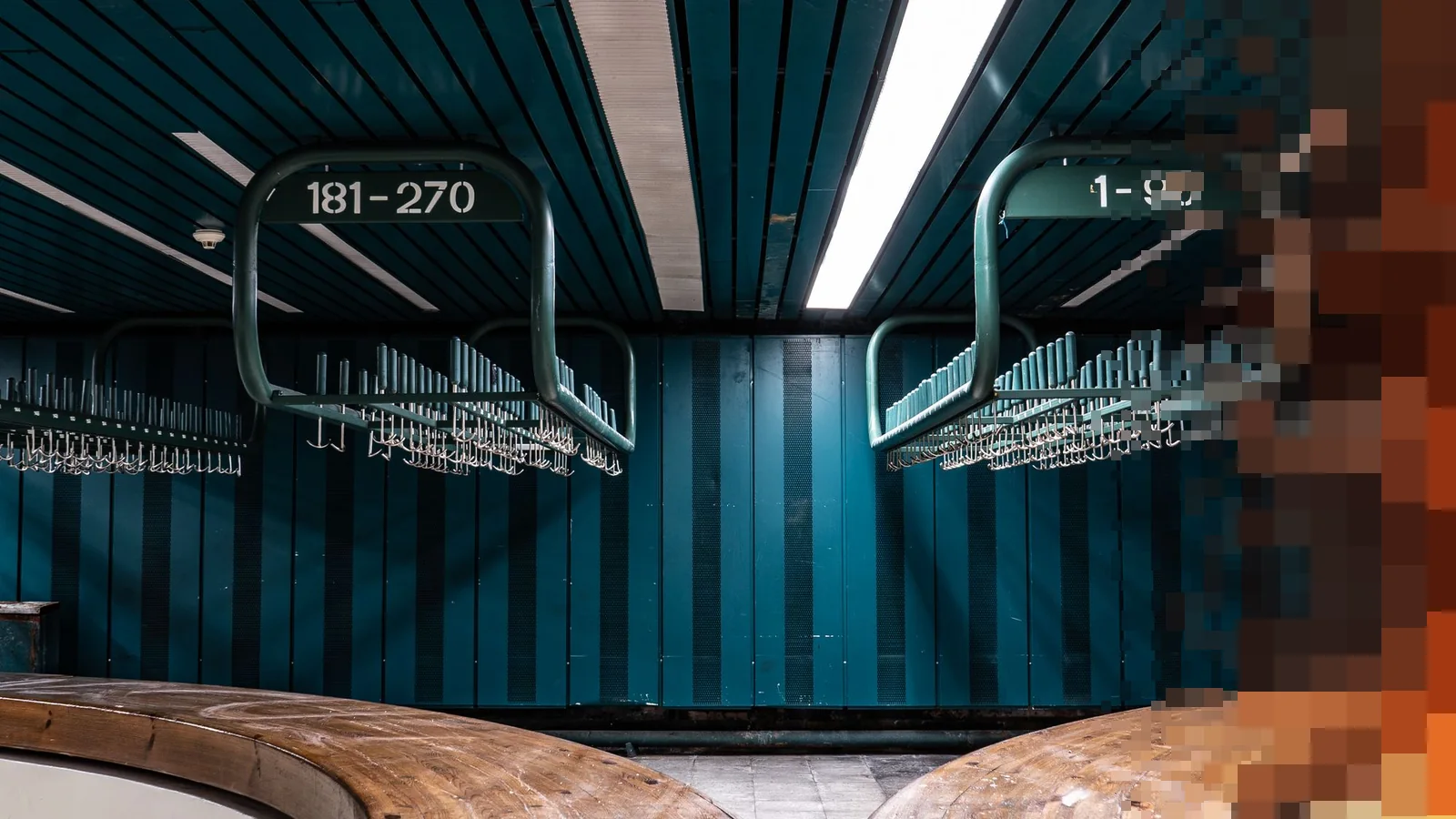 Garderobe i en konsertsal med nummererte stativer og knagger under taket