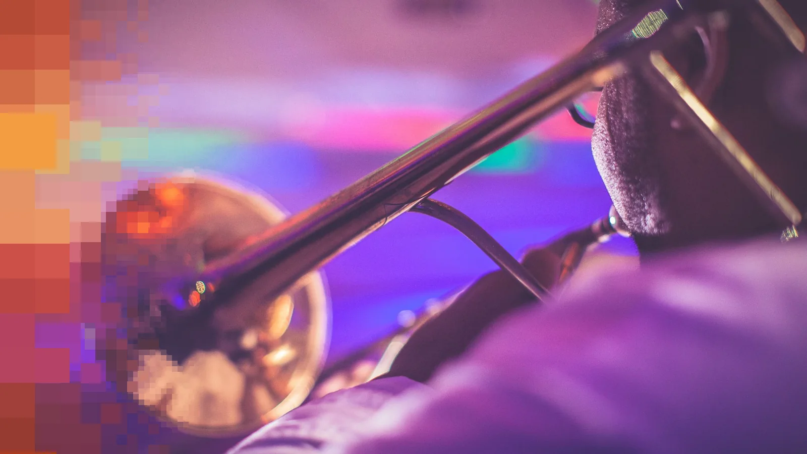 Trompetist sett bakfra med instrumentet i fokus foran lilla og rosa scenelys