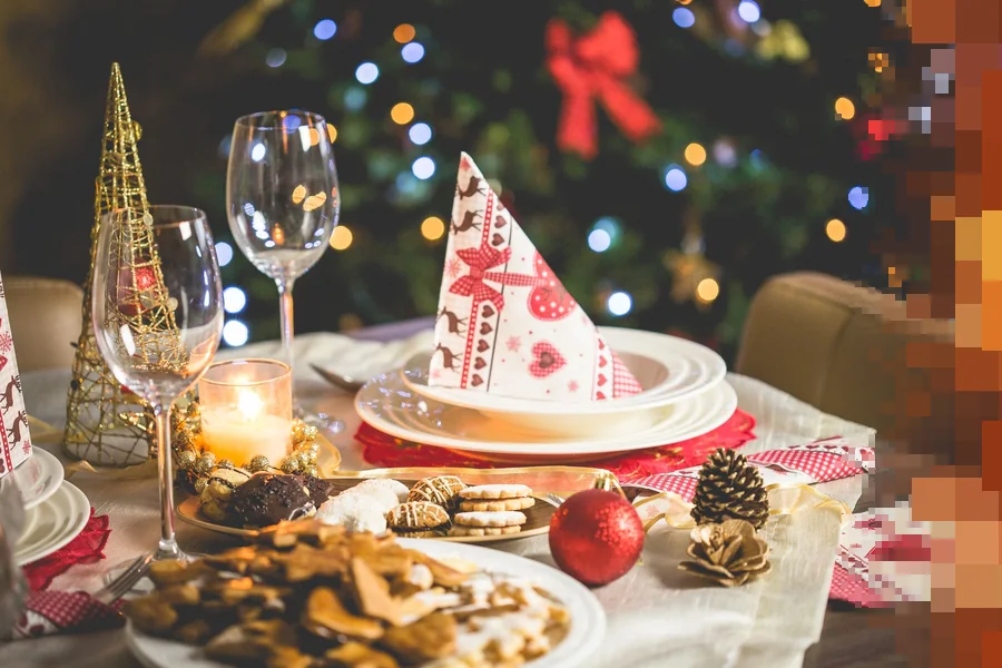 Et pyntet julebord med vinglass, levende lys, julekuler og pepperkaker