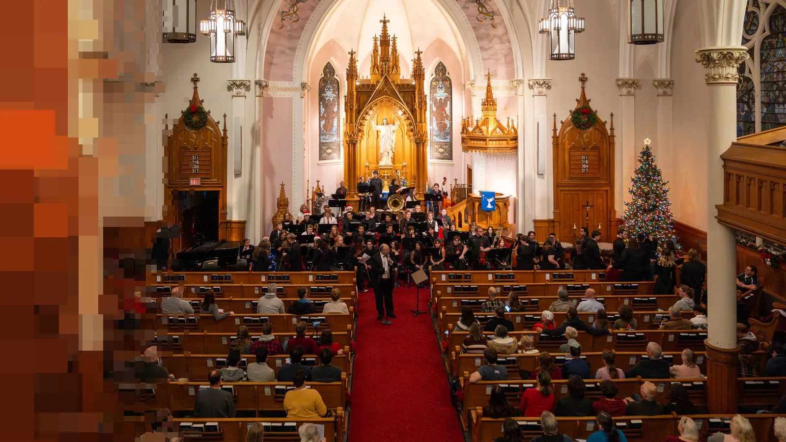 En fullsatt kirke under en julekonsert, med juletre og orkester foran koret