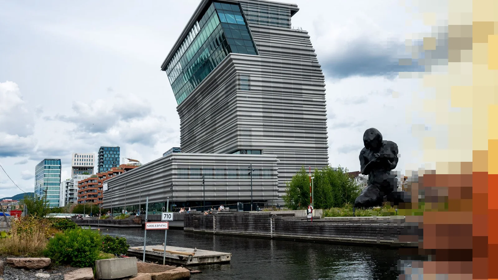 MUNCH-bygget i Bjørvika sett fra vannkanten, med den store bronseskulpturen Moren til høyre