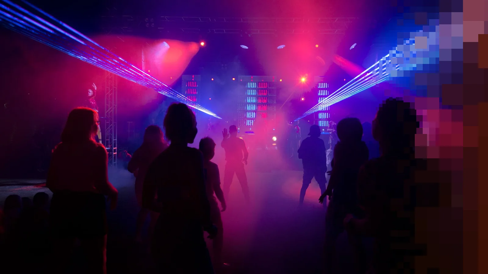 Silhuetter av folk som danser på et klubbgulv under lilla og rosa lys og laserstråler