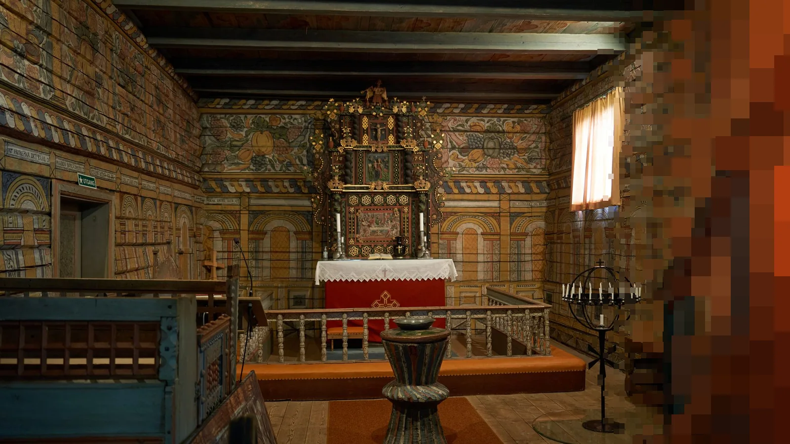 Interiøret i en gammel norsk stavkirke med malte vegger, alter og døpefont