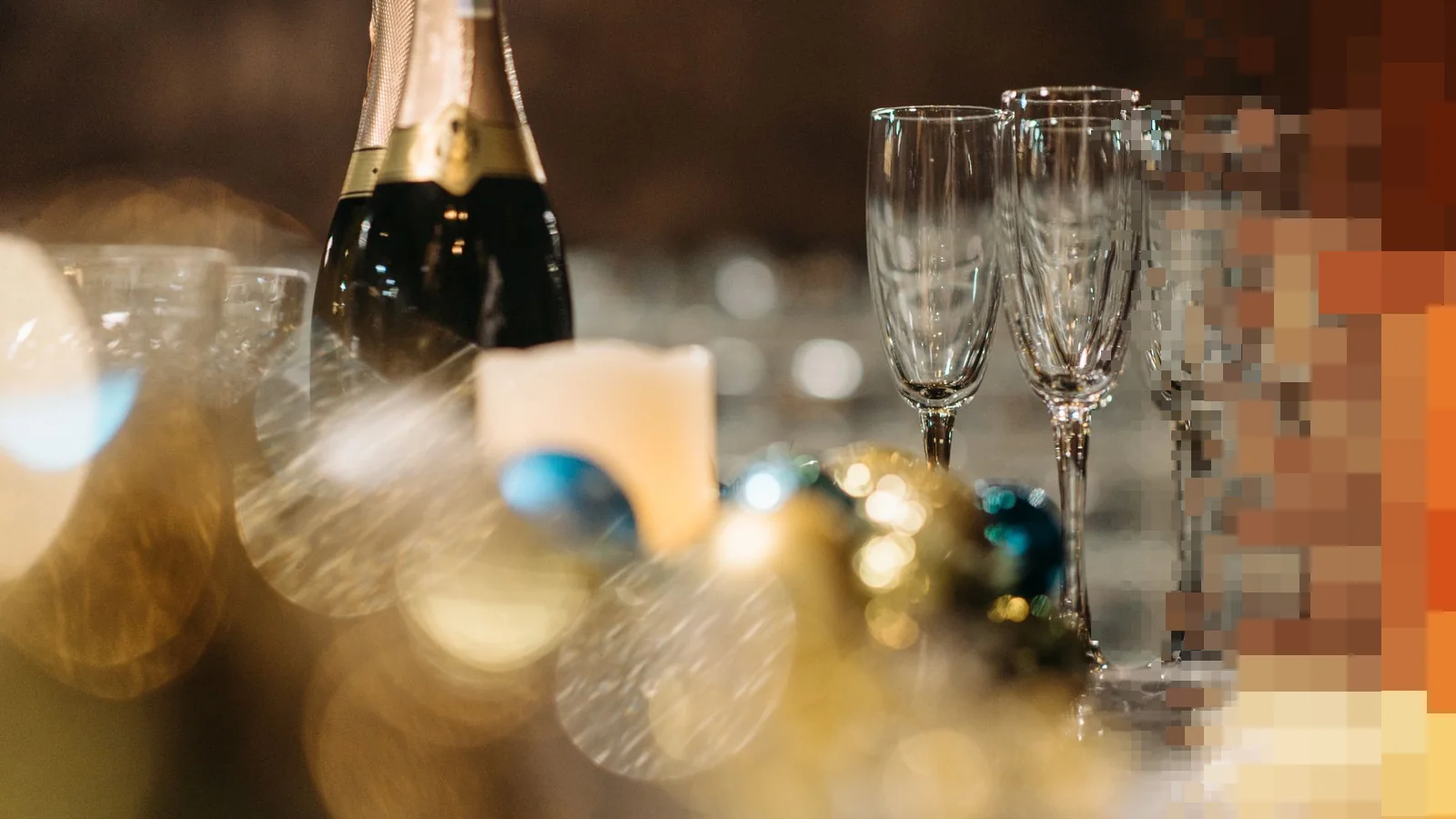 Champagneflaske og høye glass med gyldne lysprikker i bakgrunnen