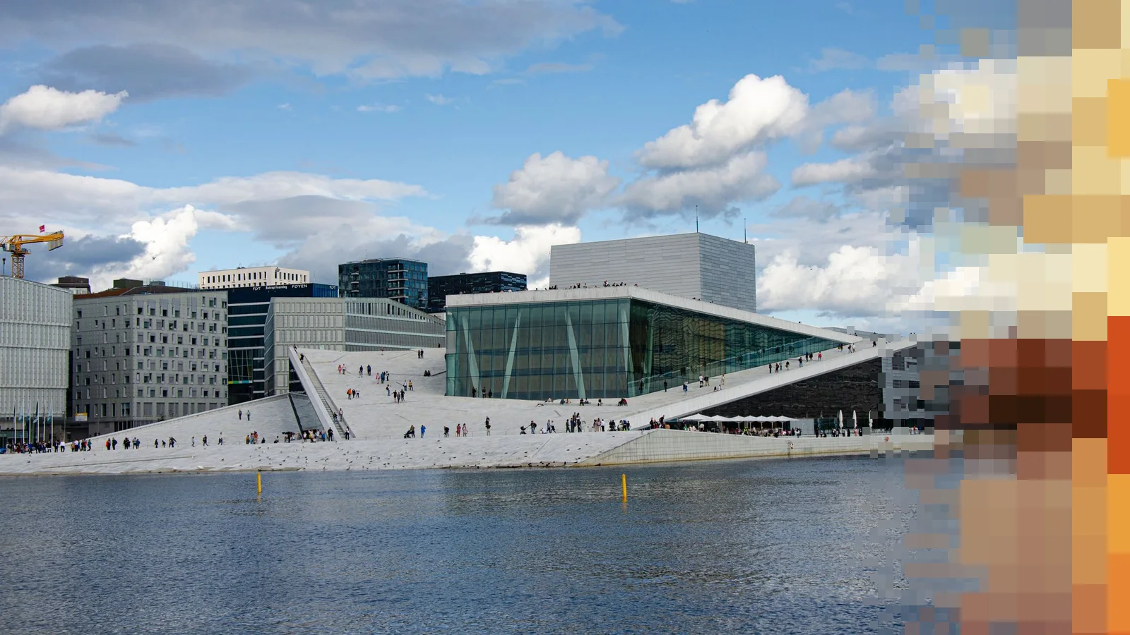 Operaen i Oslo sett fra vannet en dag med skyer, med folk som går på det skrå marmortaket