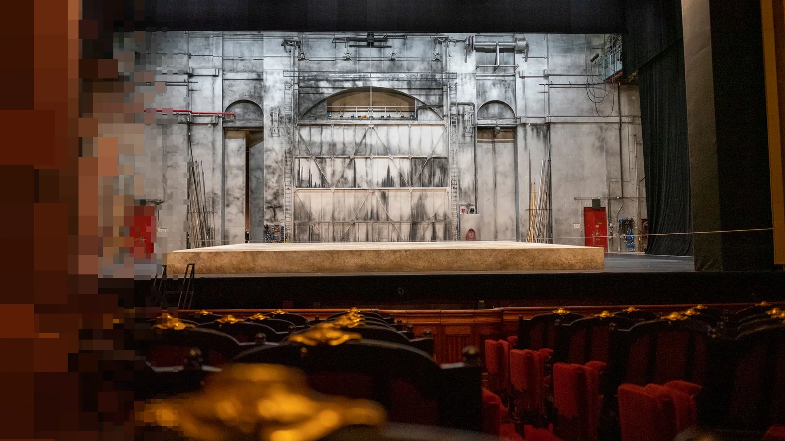 Scene med grå bakvegg og tomme seterader i et teater