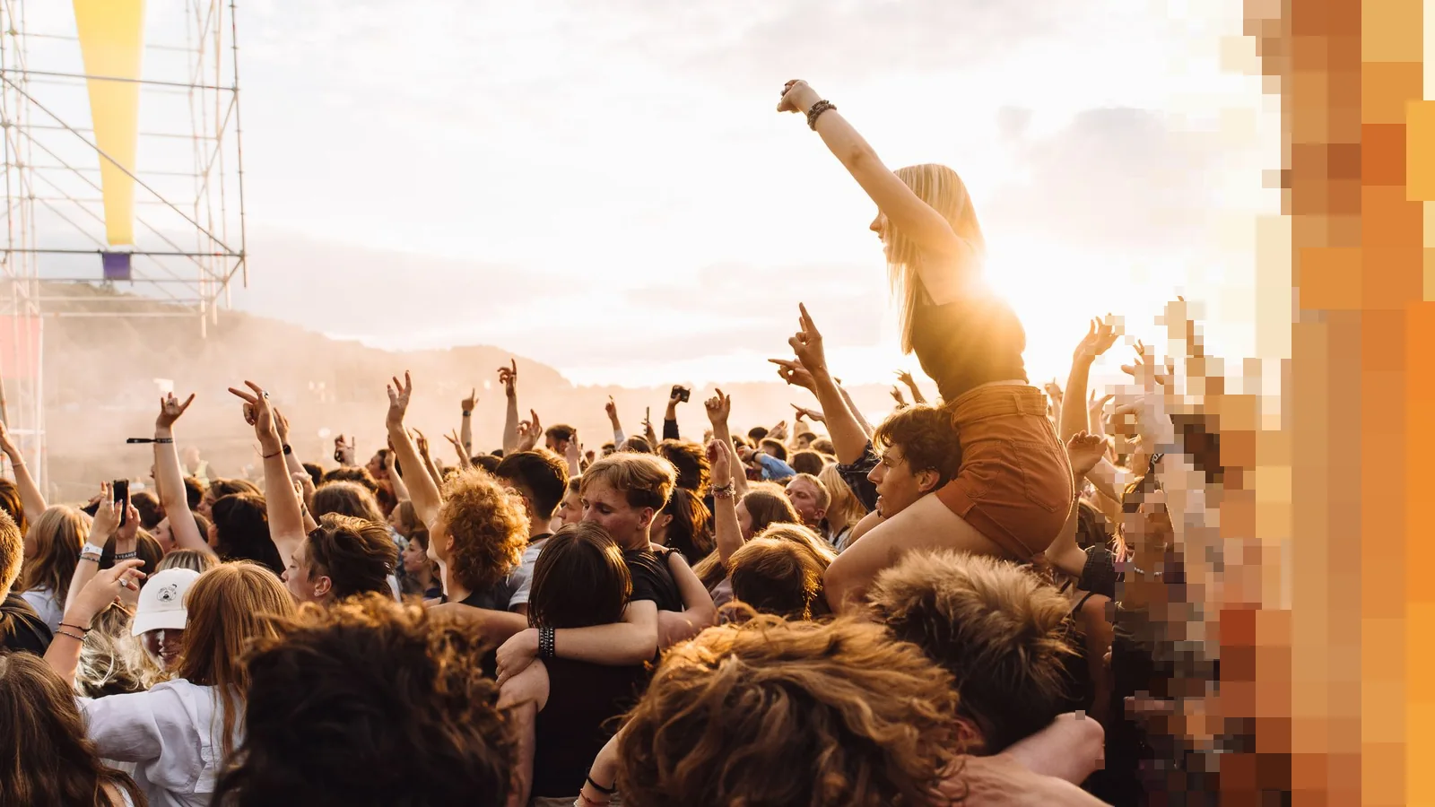 Festivalpublikum med armene i været foran en scene i motlys fra kveldssolen